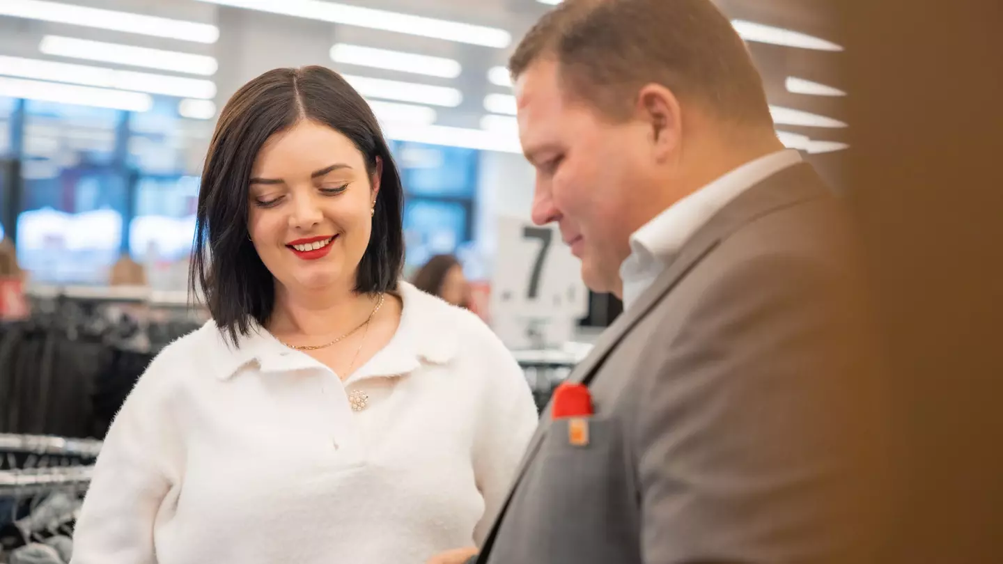 Twee medewerkers kijken glimlachend naar een voorwerp in de winkel