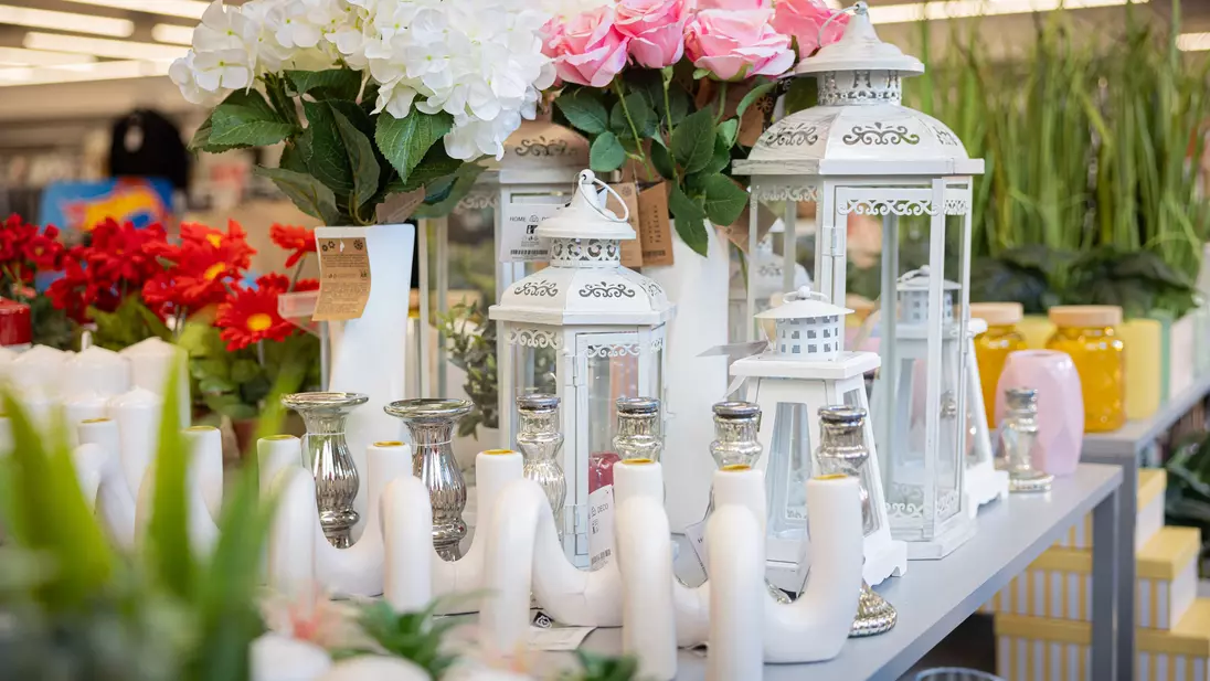 Decoratieartikelen en kunstbloemen, onderdeel van het non-foodassortiment van KiK, worden gepresenteerd op een traptafel in de entreezone