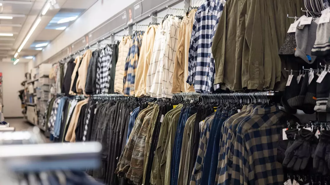 Herenkleding aan kledingstangen aan de achterwand van een KiK-filiaal