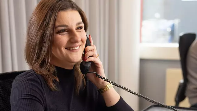 Een vrouw zit op haar werk te bellen en glimlacht