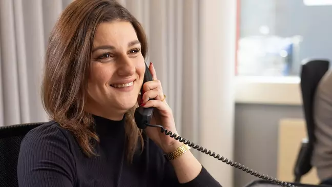 Een vrouw zit op haar werk te bellen en glimlacht