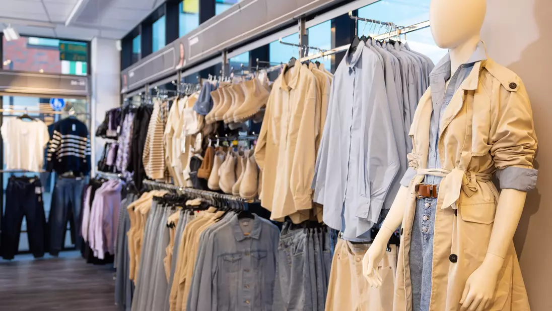Productpresentatie in complete outfits tegen de achterwand van een KiK-filiaal