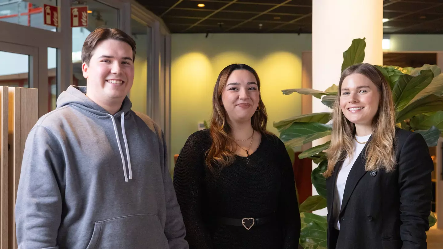 Drie medewerkers glimlachen vriendelijk naar de camera