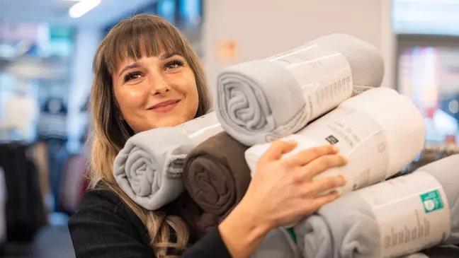Een jonge medewerkster legt dekens in de schappen van een KiK-filiaal