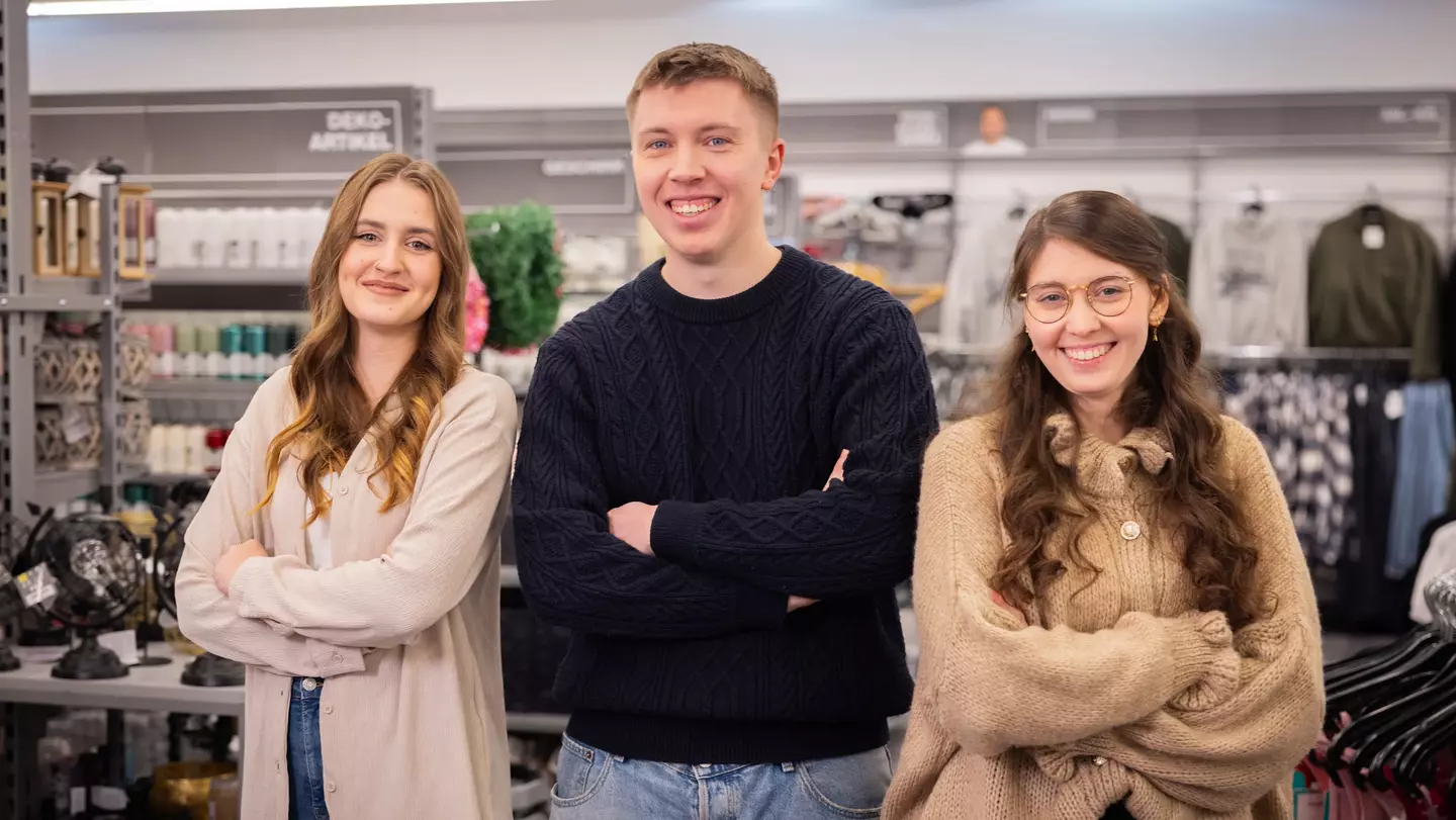 Drie medewerkers staan glimlachend in een filiaal