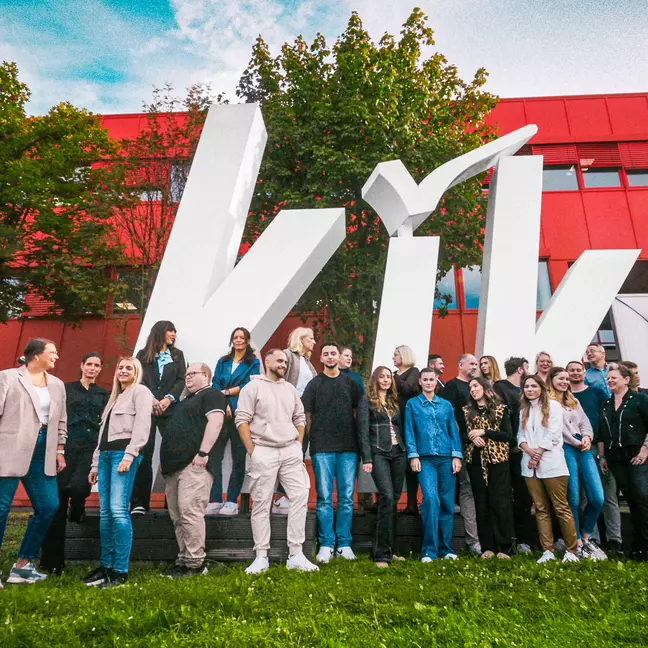 Medewerkers poseren voor het hoofdkantoor in Bönen, voor een groot KiK-logo, voor een groepsfoto