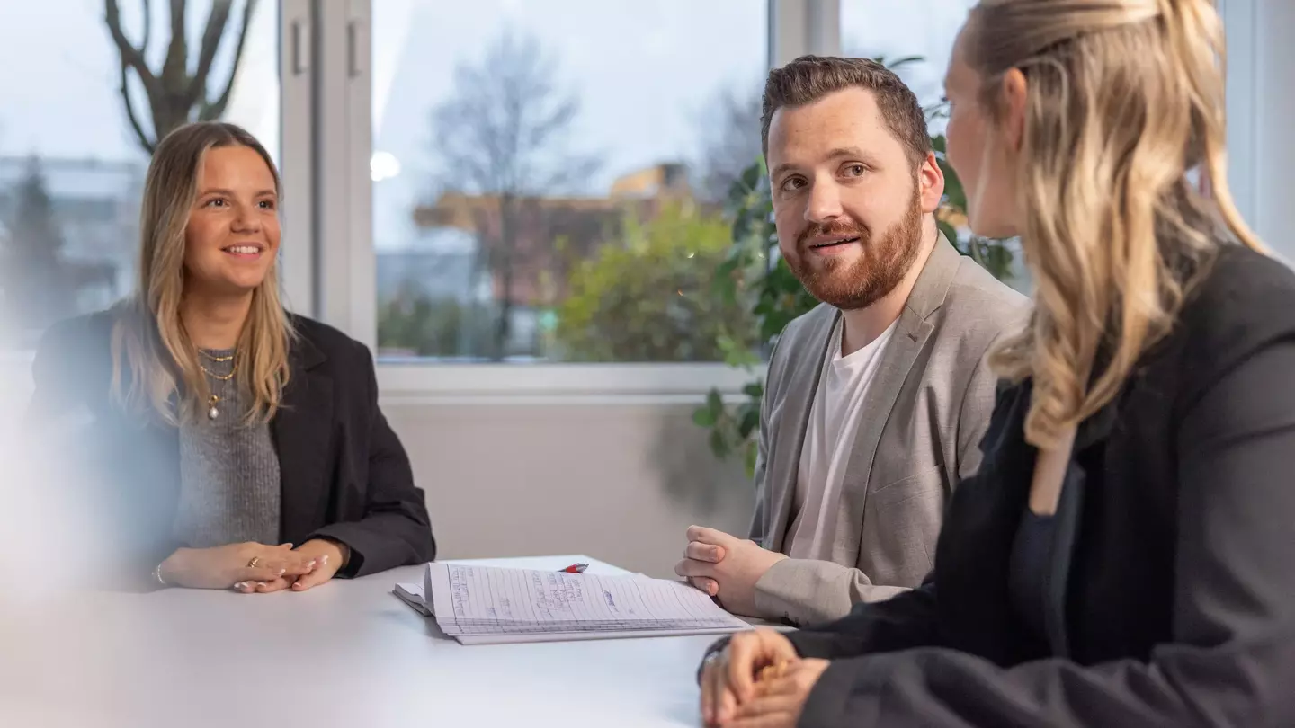 Drie personen zitten tijdens een sollicitatiegesprek in een modern kantoor