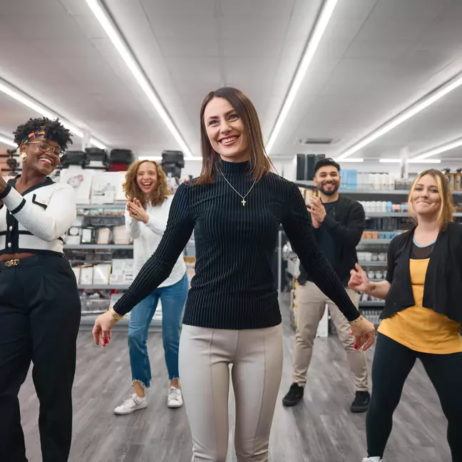 Collega's dansen en lachen in de winkel.